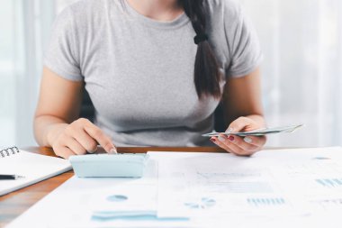 Genç Asyalı kadın yığınla para kazanıyor. Yatırım tasarruf konsepti, tasarruf, yatırım. Masada yığınla bozuk para ve banka hesap makinesi, tasarruf etmek için para ve gelir elde etmek için yatırım..