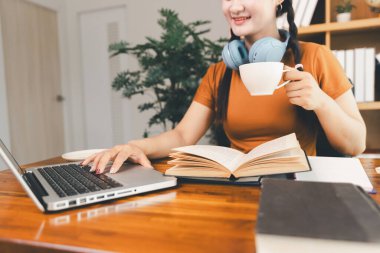 Kadın dizüstü bilgisayarda çalışıyor, not defterine not alıyor, internetten ders çalışıyor, Webinar izliyor, bilgisayar kullanıyor, kontrol listesi yazıyor. Uzaktan eğitim, e öğrenme konsepti.