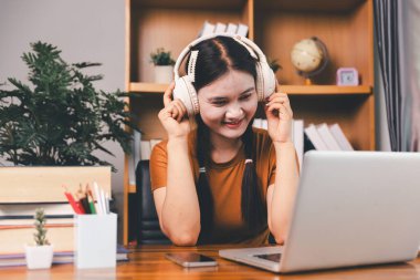 Asyalı kız ev ödevi yapıyor ve evde çalışıyor. Masa başında dizüstü bilgisayar kullanan bir kadın webinar izleyen, online çalışan, internet dersine giren ya da evden kumandalı sanal telefon görüşmesi yapan notlar yazıyor..