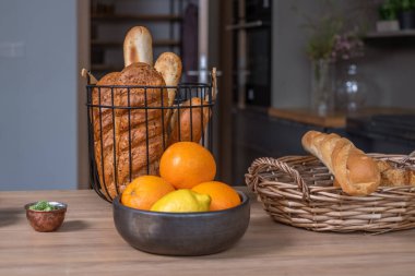 Two baskets with bread and French baguettes on a wooden kitchen table with a kitchen in the background, a bowl of oranges. food advertising poster,. High quality photo
