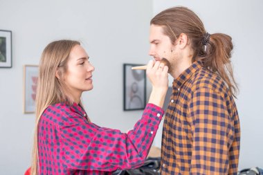 Oturma odasında ekose gömlekli genç bir çift. Genç bir kadın.