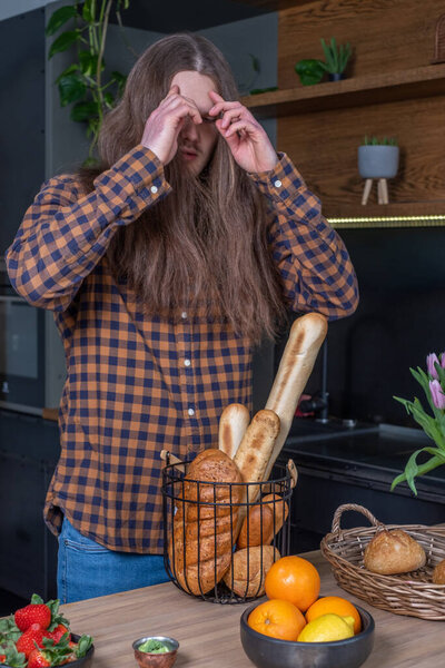 Wooden table with bread and fruit. A long-haired man in a checke
