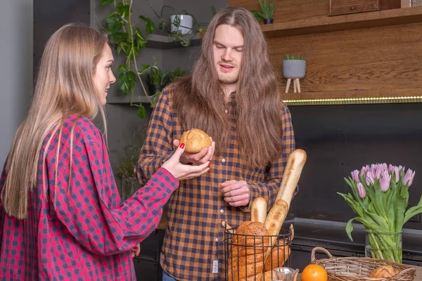 stock image Young smiling couple in checkered shirts in kitchen with bread i