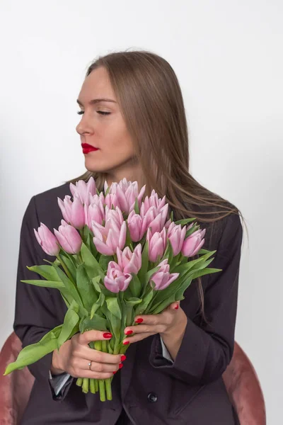 stock image Beautiful woman in a suit holding a pink bouquet of tulips. Seri