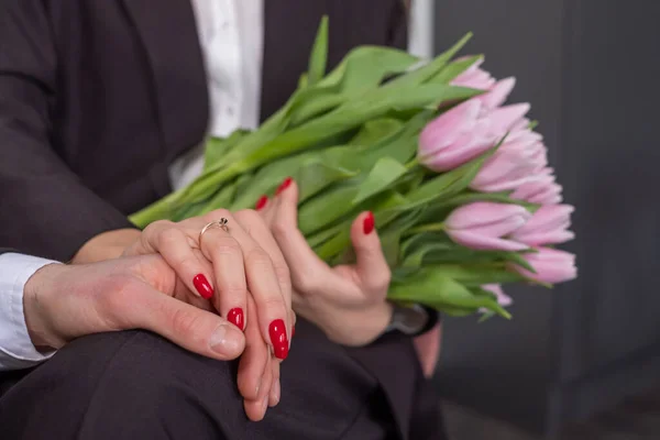 Engagement ring on woman's right hand. Couple wearing black suit