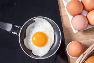 Fırının üstünde küçük siyah bir tavada taze pişmiş yumurta. Fre