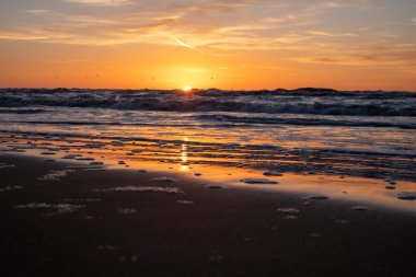 Muhteşem, düşünceli, rengarenk bir gün batımı arka planda kışın sonunda deniz kıyısında. Deniz, ufuk ve güneşin yolu..