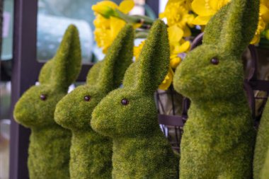 Şirin, neşeli, büyük yosun yeşili Paskalya tavşanları. Arkadaki sepette sarı nergis buketi..