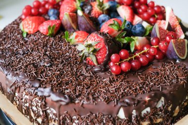 Koyu çikolata, taze incir, böğürtlen, çilek ve üzümle süslenmiş lezzetli bir pasta. Çikolata parçacıklı iştah açıcı pasta. Çikolata severler için reklam. Pastane posteri