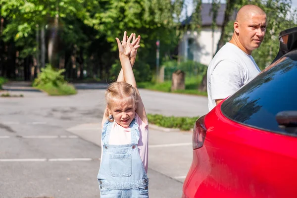 Dad and daughter near a red car on a sunny summer day. Copy space. High quality photo
