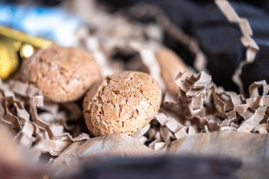 Sürdürülebilir kağıt parçalarında Amaretto kurabiyeleri. Küçük bir altın rendesi ve arka plandaki şişede bir içki. Uzayı kopyala Yüksek kalite fotoğraf