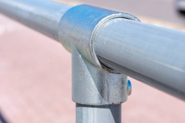 Metal boru ipliklerle bağlanıyor. Arka planda, güneşli bir yaz gününde açık bir kaldırıma beyaz bir şerit çizilir. Uzayı kopyala Alıntılar için arka plan. Yüksek kalite fotoğraf