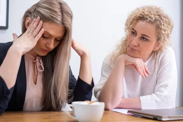 A distressed young woman in business attire is comforted by a concerned colleague, embodying the emotional toll of business failure and the need for support during tough times. High quality photo