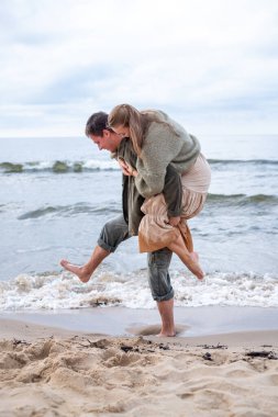 Spontane bir sırtüstü yatma anı, deniz kenarında oynayan bir çifti yakalar, dalgalar nazikçe birlikteliğin bir anlık görüntüsünü çarpıştırır ve neşeyi paylaşır. Yüksek kalite fotoğraf