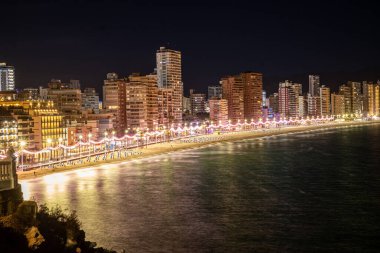 Gece vakti deniz manzarası canlı sokak ışıklarıyla aydınlatılıyor. Sudaki yansımalarla ve canlı kentsel atmosferle. Yüksek kalite fotoğraf