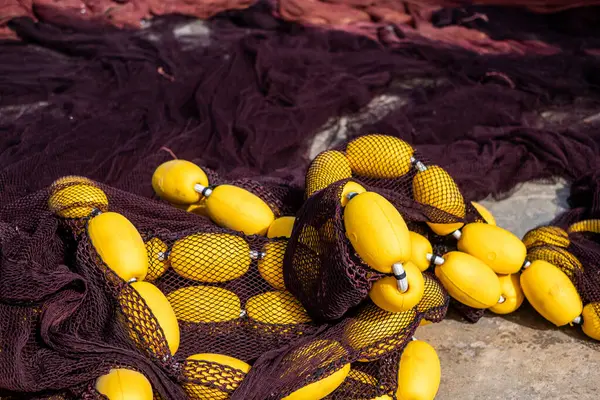Bright yellow buoys entangled in dark fishing nets on a dock, symbolizing the fishing industry and maritime work. High quality photo