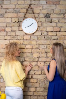Two business partners, woman stand under a watch and talk , suggesting a moment of urgency and the importance of punctuality in professional growth. High quality photo clipart