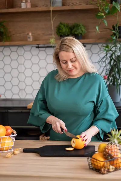 Modern mutfak kadınlarında taze portakallar dilimlenir, ahşap tahtada bıçakla narenciye meyveleri kesilir, sağlıklı bir yemek pişirme biçimi konseptini temsil eder.