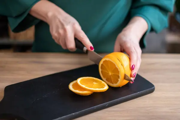Koyu renk kesim tahtasında olgun turuncu kesen, parlak meyve renkleri sergileyen, mutfak ortamında çekilen, beslenme konsepti