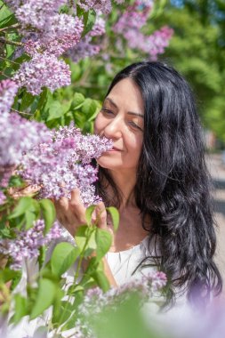 Bayan leylak çiçeklerinin kokusunu sever, açık havada sakin bir an, sakin bir bahar sahnesi, çiçek açan güzellik, rahatlama konsepti.
