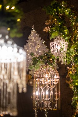 Işıl ışıl parlayan ışıklar, avize, beyaz bir Noel ağacı ve yemyeşil bir yeşillik ile çok güzel düzenlenmiş bir ortamı aydınlatarak şenlikli bir atmosfer yaratıyor..
