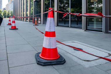 Trafik konileri kaldırım boyunca konumlandırıldı, dikkat bantlarıyla güvenlik altına alındı, bir inşaat alanı belirlendi, yakınlardaki yaya ve araçların güvenliği sağlandı