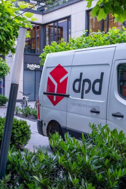 Varşova, Polonya - 10 Temmuz 2025: DPD dağıtım aracı yemyeşil ve çağdaş binalarla çevrili canlı bir şehir merkezine park edilmiştir.