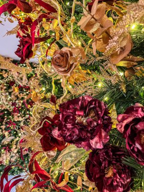 Kırmızı ve altın elementlerle süslenmiş dekoratif bir çiçek düzenine yakından bakmak, çiçek ve yeşilliğin dokusunu vurgulamak, şenlikli kutlamalar için mükemmel.