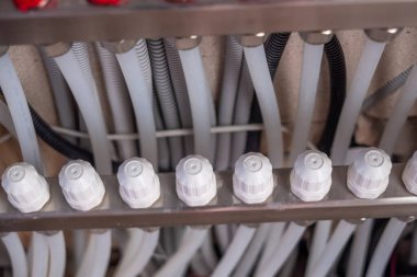 Metal panelde beyaz valfleri ve gri hortumları olan tesisat sisteminin ayrıntılı yakın çekimleri, bağlantıları ve endüstriyel tasarımı vurguluyor, işlevsellik ve yapıyı vurguluyor