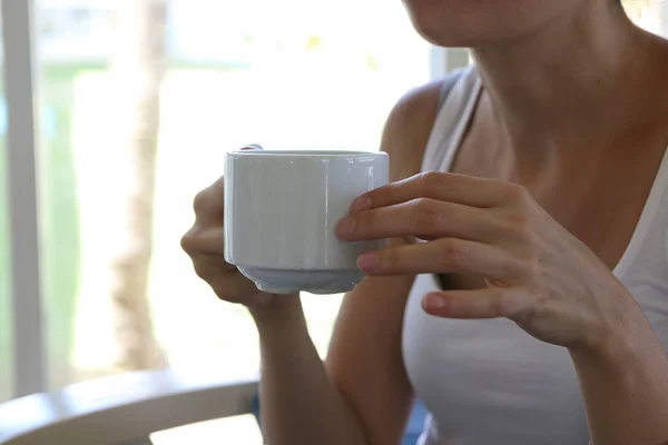 Woman in white relaxes with a cup of tea on vacation