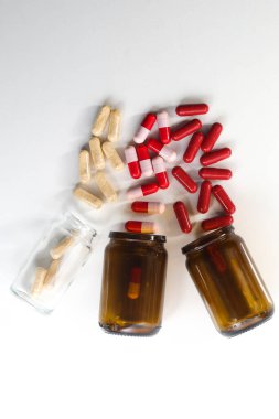 Beyaz arka planda çok renkli probiyotik ve antibiyotik kapsülleri olan üç şişenin üst görüntüsü.