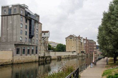 Bulutlu bir Eylül öğleden sonra Bath City Center 'ın güneyinden geçen Avon Nehri manzarası. Rıhtım boyunca bulunan eski sanayi depoları apartman ve ofislere dönüştürüldü..