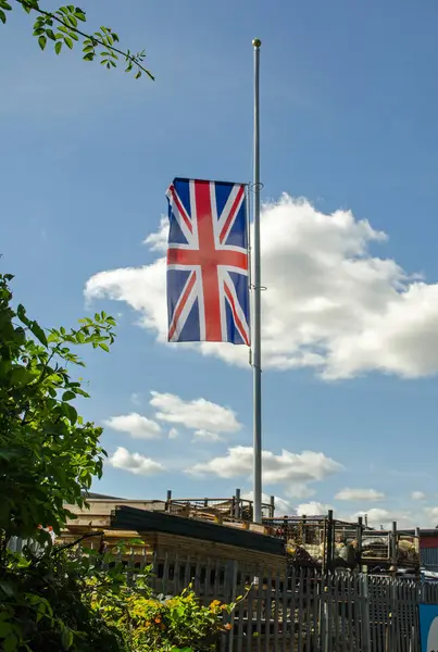 stock image A union flag, commonly known as a union jack, flying at half mast as a sign of respect.