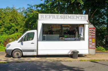 17 Eylül 2022: Gururlu kebap minibüsü operatörleri güneşli bir cumartesi öğleden sonra Grafton Yolu, Basingstoke 'daki araçlarında işaret veriyorlar..