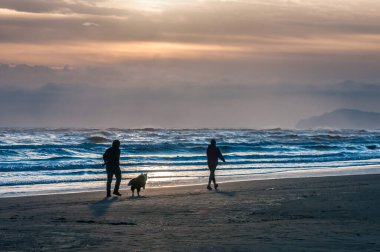 people walking around on the beach at sunrise