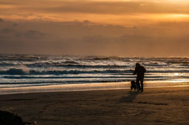 man walking around on the beach at sunrise