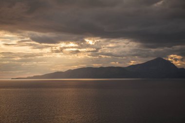 Gün batımında adanın arkasında deniz fırtınası