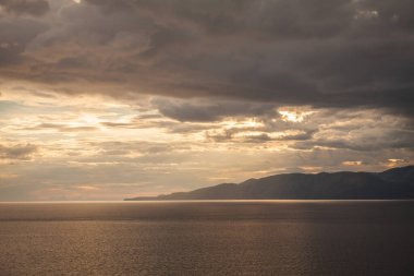 Gün batımında adanın arkasında deniz fırtınası