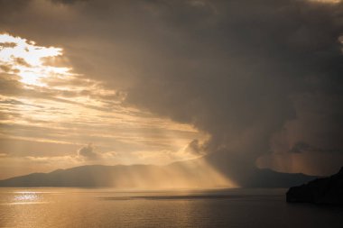 Gün batımında adanın arkasında deniz fırtınası