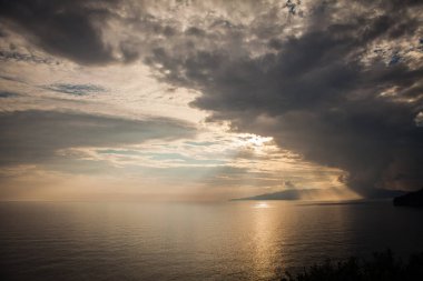 Gün batımında adanın arkasında deniz fırtınası