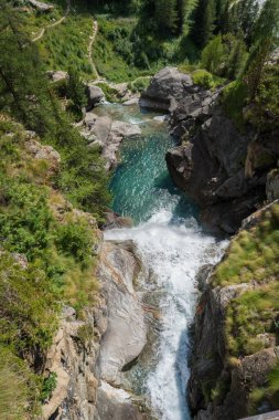 Kayaların arasında akarak Alp Şelalesi oluşturur.