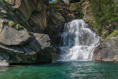 Kayaların arasında akarak Alp Şelalesi oluşturur.