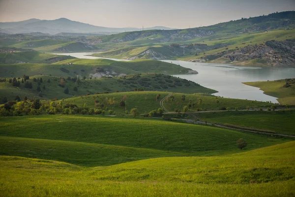 山の中の湖と緑の牧草地の風景 — ストック写真