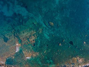 Uçurumun ve şeffaf mavi suyun havadan çekilmiş fotoğrafı.
