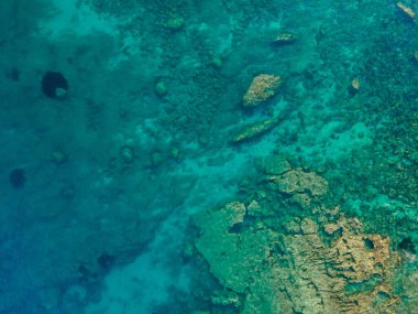 Uçurumun ve şeffaf mavi suyun havadan çekilmiş fotoğrafı.