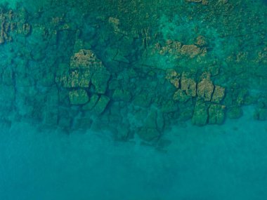 Uçurumun ve şeffaf mavi suyun havadan çekilmiş fotoğrafı.