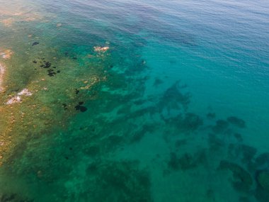 Uçurumun ve şeffaf mavi suyun havadan çekilmiş fotoğrafı.