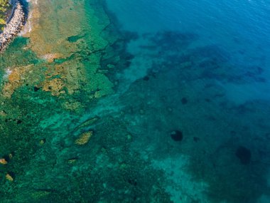 Uçurumun ve şeffaf mavi suyun havadan çekilmiş fotoğrafı.