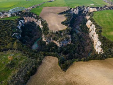 Gravina nehrinin geçitleri, kayaların üzerine oyulmuş kanyonlar ve ekili tarlalar.