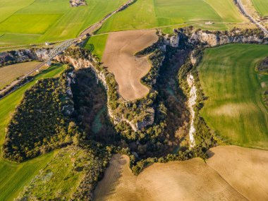 Gravina nehrinin geçitleri, kayaların üzerine oyulmuş kanyonlar ve ekili tarlalar.